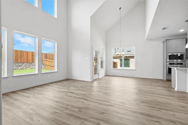 Unfurnished living room featuring a towering ceiling, plenty of natural light, a chandelier, and light wood-style flooring | Image 12