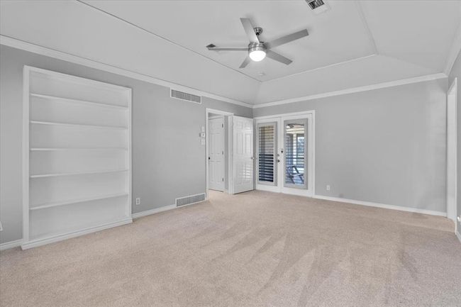 Unfurnished bedroom featuring ceiling fan, lofted ceiling, light colored carpet, and ornamental molding | Image 10