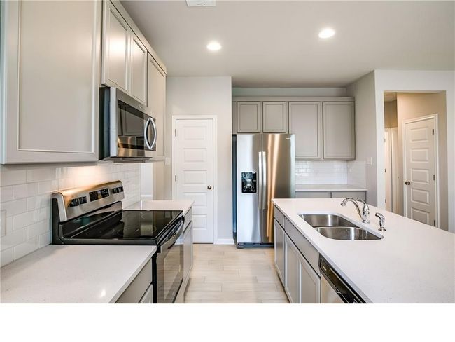 Kitchen featuring appliances with stainless steel finishes, gray cabinetry, decorative backsplash, light countertops, and recessed lighting | Image 10