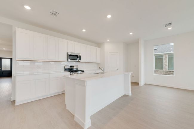 Kitchen featuring stainless steel appliances, a sink, light wood finished floors, a center island with sink, and recessed lighting | Image 7