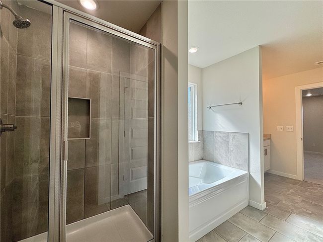 Pamper yourself in the lavish master bathroom, featuring a generously sized walk-in shower that envelops you in a cascade of soothing water or relax in the tub, while the double sinks provide ample space for personal care routines and a touch of modern elegance. | Image 13