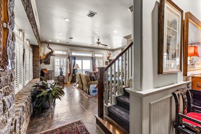 Stepping into this home, it is easy to see how well built it is. Exposed stone walls with casement windows and plantation shutters, slate floors, and wood paneling are modeled after the Tremont House Hotel in Galveston. | Image 8