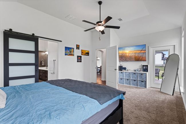 Carpeted bedroom featuring high vaulted ceiling, a barn door, a ceiling fan, and visible vents | Image 21