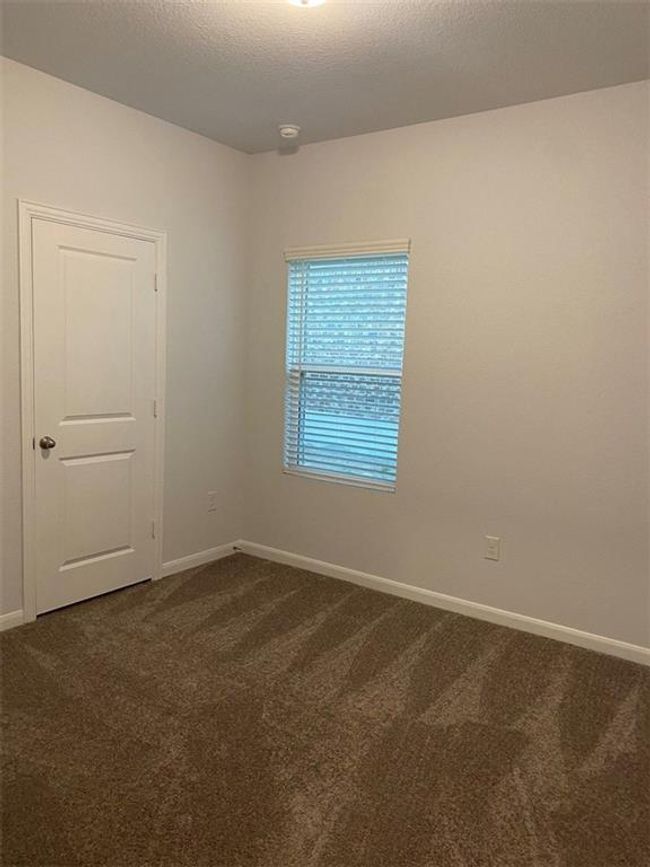 Unfurnished room featuring dark colored carpet and baseboards | Image 9