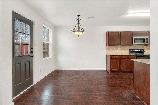 Kitchen with stainless steel microwave, black electric range, dark wood-style flooring, decorative light fixtures, and decorative backsplash | Image 11