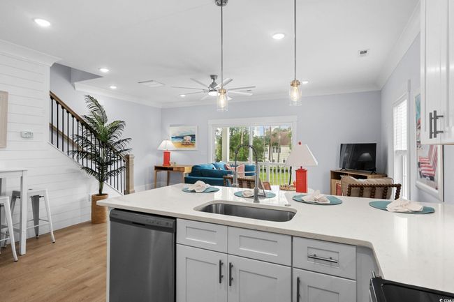 Kitchen with open floor plan, dishwasher, light stone countertops, light wood-style flooring, and ornamental molding | Image 8