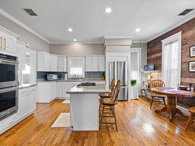 Kitchen with stainless steel appliances, a breakfast bar area, white cabinets, and light wood finished floors | Image 17
