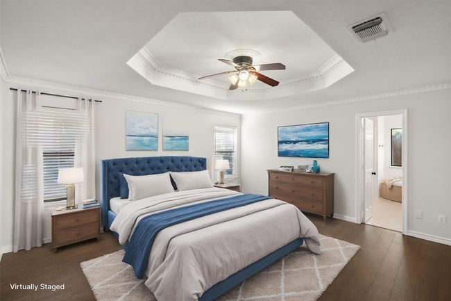 This primary bedroom is a retreat after a long day. Located at the back of the home for privacy, this room is spacious. It features windows for natural light, engineered wood floors, an inset ceiling with fan and crown molding. | Image 29