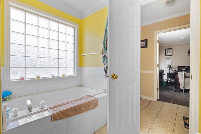 Full bathroom with a relaxing tiled tub, tile patterned flooring, and ornamental molding | Image 12