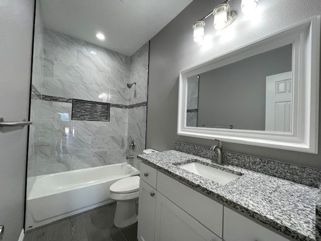 Full bathroom featuring bathtub / shower combination, granite top vanity, and ceramic wood look flooring | Image 23