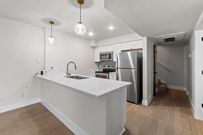 Kitchen with stainless steel appliances, a sink, light wood-style flooring, a peninsula, and recessed lighting | Image 11