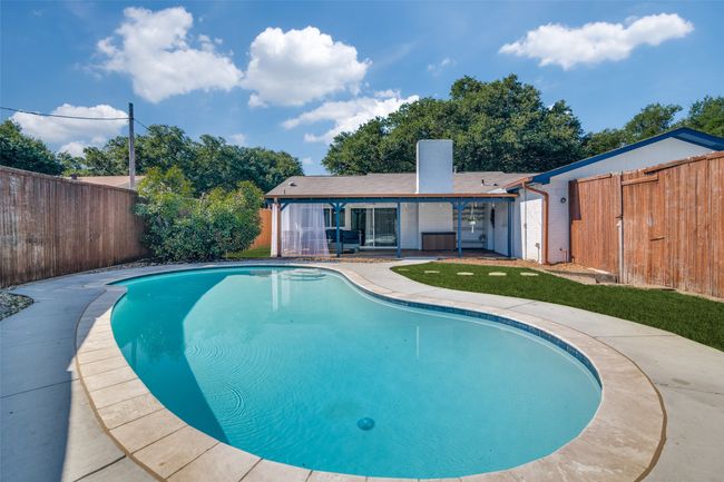 View of swimming pool with a fenced backyard and a patio | Image 17