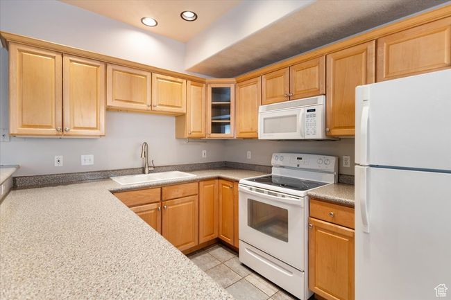 Kitchen with white appliances, recessed lighting, glass insert cabinets, light countertops, and light tile patterned floors | Image 11