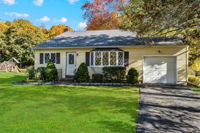 Ranch-style home with a garage, a front lawn, and a playground | Image 1