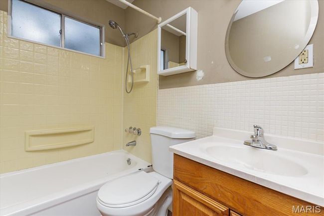 Bathroom featuring tile walls, shower / bath combination, vanity, and tasteful backsplash | Image 14