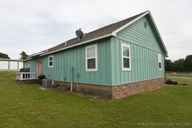 View of property exterior featuring board and batten siding, cooling unit, a yard, and a shingled roof | Image 27