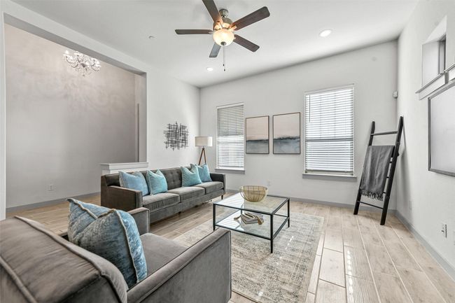 Living room featuring light hardwood / wood-style floors and ceiling fan with notable chandelier | Image 10