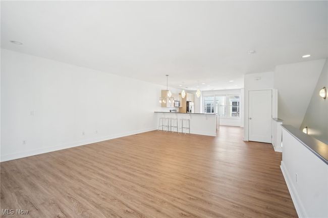 Unfurnished living room featuring an inviting chandelier, light wood-style flooring, recessed lighting, and baseboards | Image 9