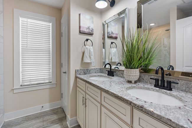 The primary bath features granite double vanities with storage space underneath. | Image 15