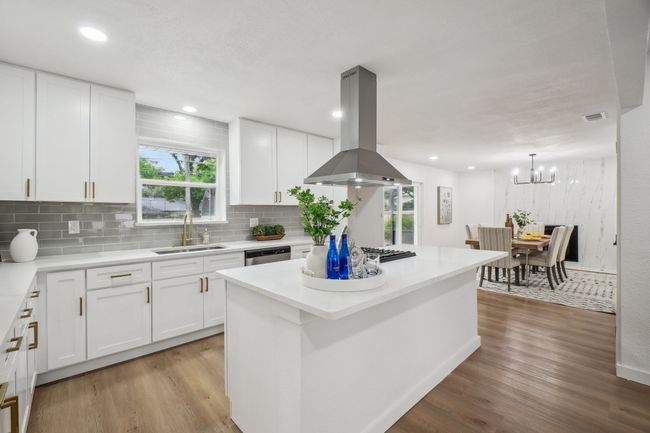 Kitchen with a sink, island exhaust hood, light wood-style flooring, stainless steel dishwasher, and decorative backsplash | Image 12