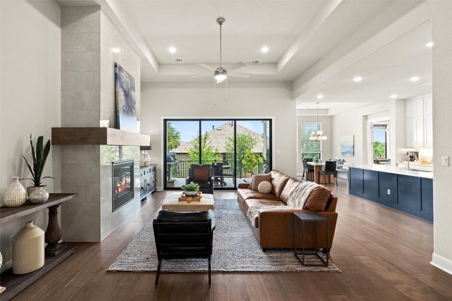 Living area featuring wood finished floors, a fireplace, a raised ceiling, recessed lighting, and a towering ceiling | Image 10