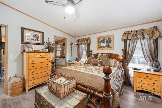 Bedroom with ornamental molding, vaulted ceiling, wood finished floors, a textured ceiling, and multiple windows | Image 19
