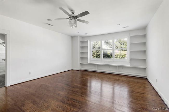 Unfurnished room featuring wood finished floors, built in shelves, baseboard heating, and ceiling fan | Image 24