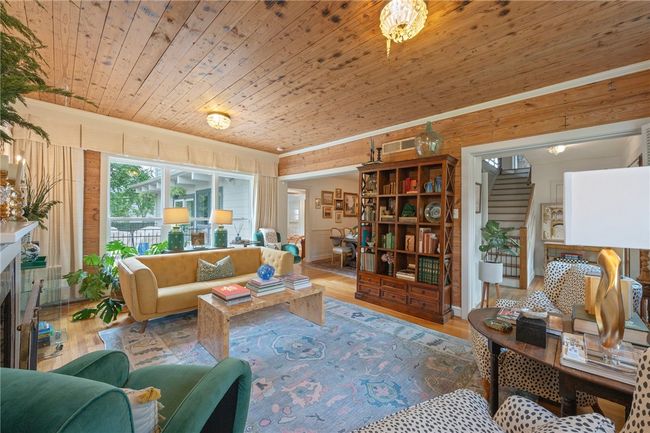 Living room with wood ceiling, wood finished floors, stairs, wood walls, and a fireplace | Image 6
