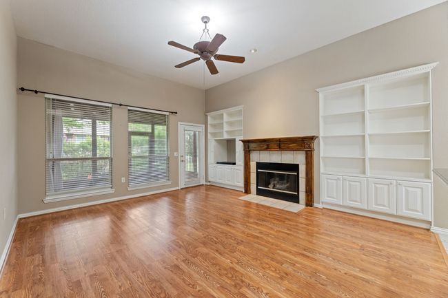 Unfurnished living room featuring built in features, a tile fireplace, light wood-type flooring, and ceiling fan | Image 19