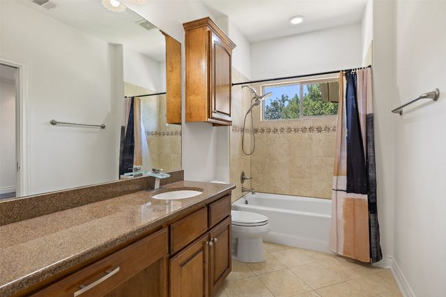 Bathroom featuring tile patterned floors, shower / bathtub combination with curtain, vanity, and toilet | Image 33