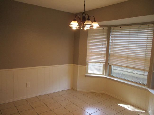 Breakfast room featuring a chandelier, light tile patterned floors, and wainscoting | Image 5