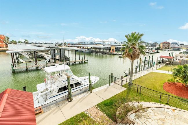 This photo showcases a waterfront property featuring a boat slip and scenic views of the marina. The area is well-maintained with a palm tree and lush lawn, perfect for boating enthusiasts and those seeking a serene waterside lifestyle. | Image 29