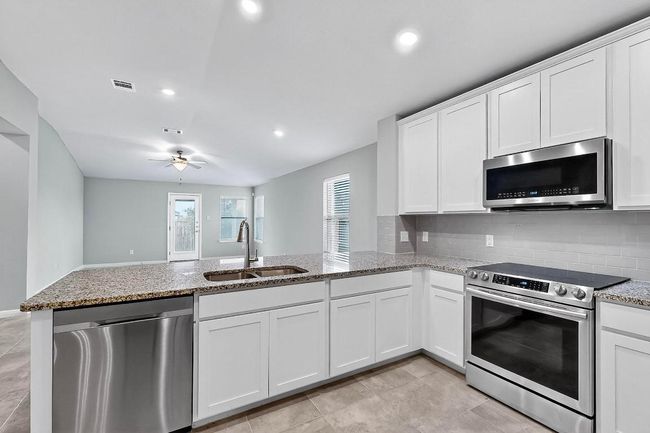 Kitchen with appliances with stainless steel finishes, a peninsula, light stone counters, and recessed lighting | Image 13