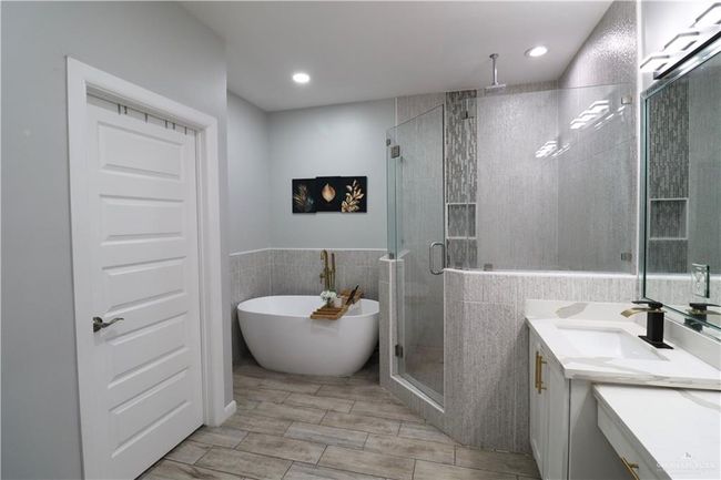 Full bath with vanity, tile walls, a shower stall, a freestanding tub, and wainscoting | Image 9