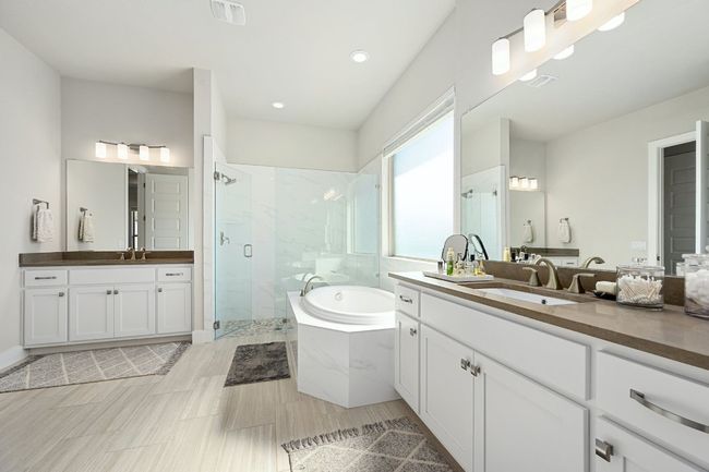 In-suite bathroom featuring dual vanities, a soaking tub, and a separate shower. | Image 16
