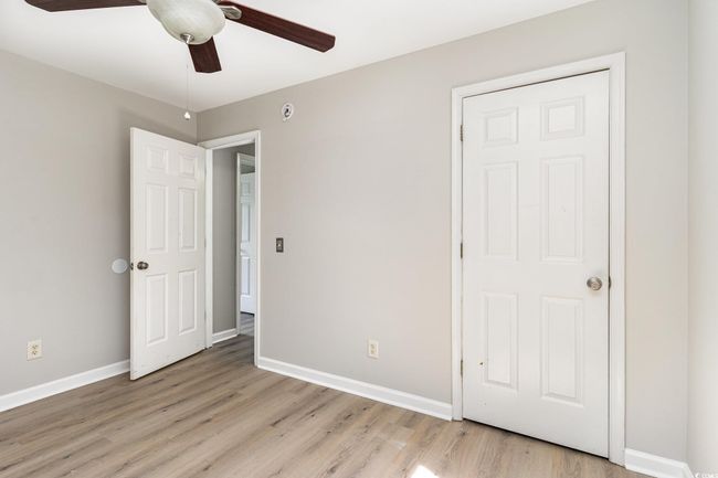 Unfurnished bedroom with ceiling fan, baseboards, and light wood-style floors | Image 16