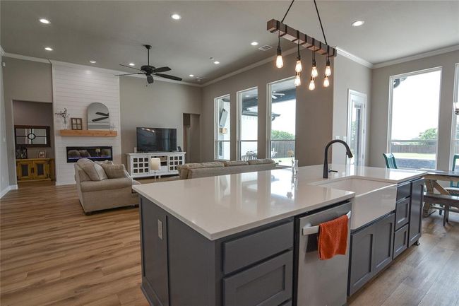 Kitchen with a center island with sink, dishwasher, a large fireplace, and wood-style flooring | Image 8