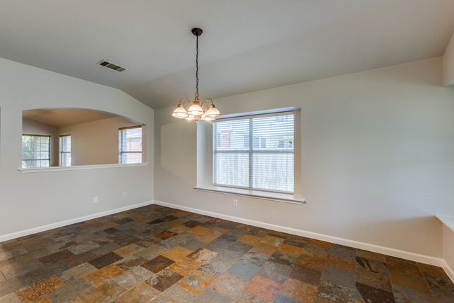Unfurnished room with stone tile flooring, plenty of natural light, arched walkways, a chandelier, and vaulted ceiling | Image 9