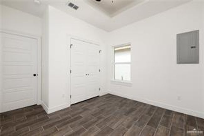 Unfurnished bedroom featuring dark wood-type flooring, electric panel, baseboards, and a tray ceiling | Image 9