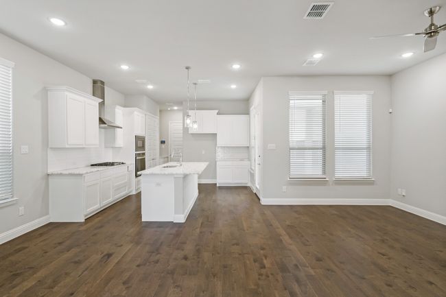 Kitchen featuring a sink, a ceiling fan, white cabinetry, wall chimney range hood, and visible vents | Image 15