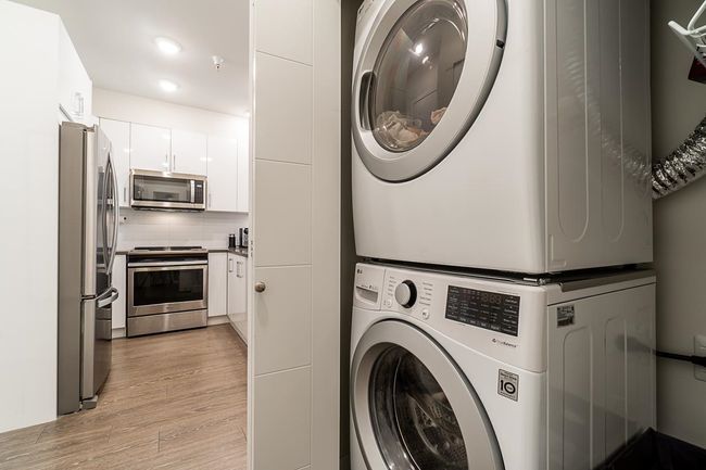 Clothes washing area with stacked washer / drying machine, light wood finished floors, and recessed lighting | Image 21