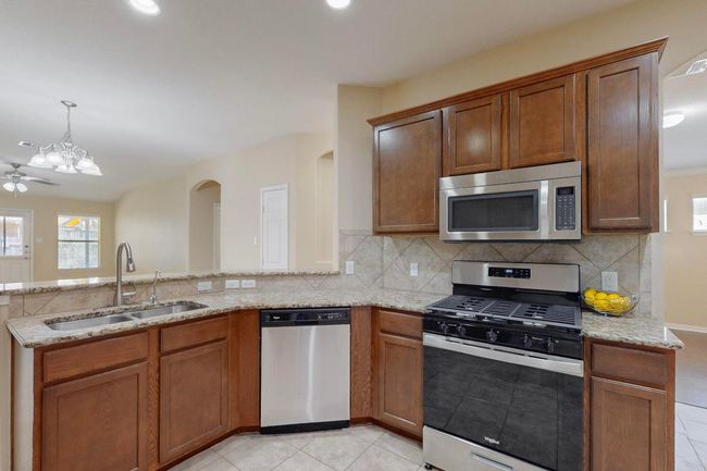 Kitchen featuring lovely backsplash, built in microwave, light tile patterned flooring, water system under sink too. There is great recessed lighting in the kitchen. | Image 4