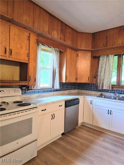 Kitchen featuring light LTV flooring, stainless steel dishwasher, white cabinets, and white range with electric cooktop | Image 3