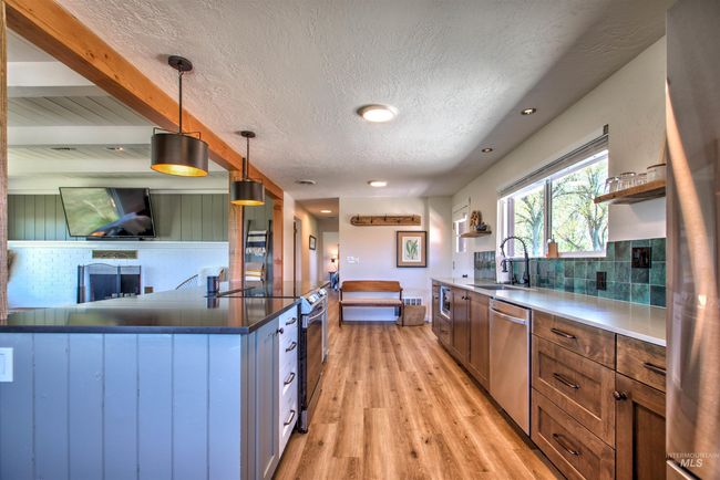 Kitchen featuring appliances with stainless steel finishes, open shelves, light wood-style flooring, tasteful backsplash, and a textured ceiling | Image 12