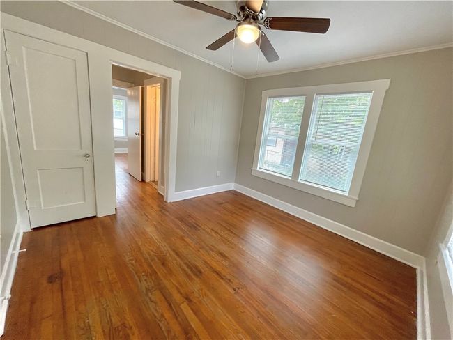Unfurnished room with ceiling fan, wood finished floors, baseboards, and ornamental molding | Image 11