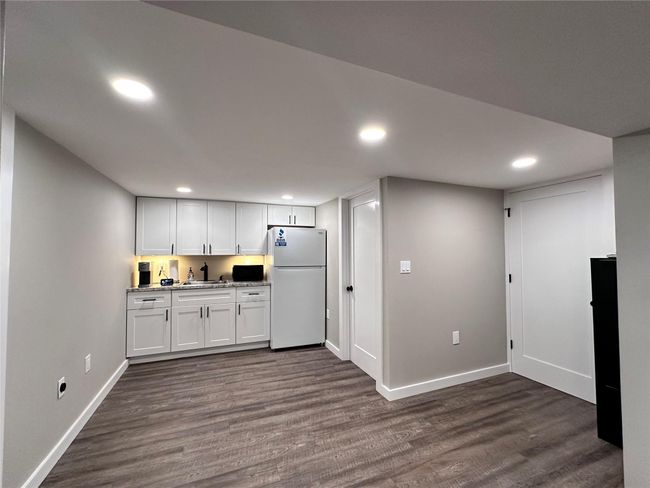 Kitchen featuring freestanding refrigerator, recessed lighting, dark wood-style floors, white cabinetry, and light stone countertops | Image 17
