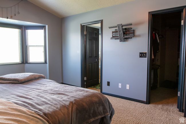 Primary Bedroom featuring a walk-in closet, carpet floors, lofted ceiling, a closet, and connected bathroom | Image 13