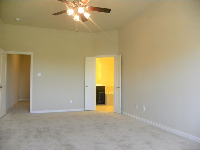 Unfurnished bedroom with light colored carpet, ensuite bath, a ceiling fan, and vaulted ceiling | Image 22