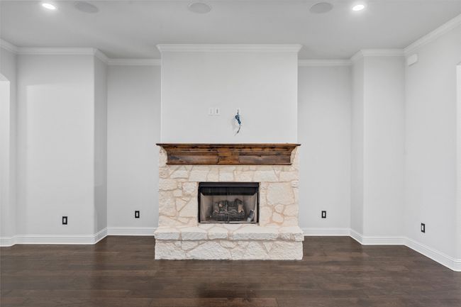 Unfurnished living room featuring wood finished floors, recessed lighting, a stone fireplace, and crown molding | Image 6