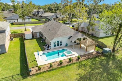 This is a single-family home featuring a spacious backyard with an in-ground pool, a hot tub, and a covered patio area with a thatched-roof structure, all enclosed by a metal fence. | Image 1